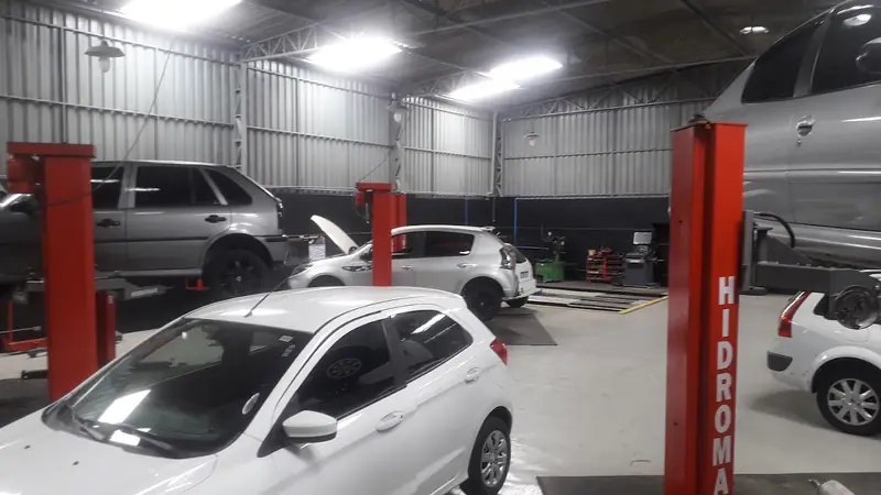 Elevadores vermelhos e carros no galpão da oficina